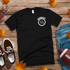May include: Black t-shirt with a white graphic of a gear shift pattern and the text "Enthusiast".
