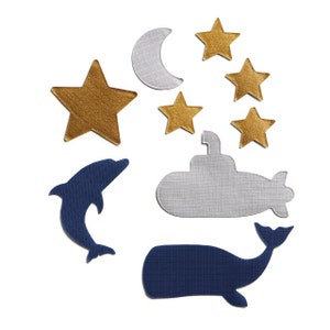 May include: A set of felt appliques featuring a crescent moon, stars, a dolphin, a whale, and a submarine. The appliques are in shades of blue, gold, and gray.