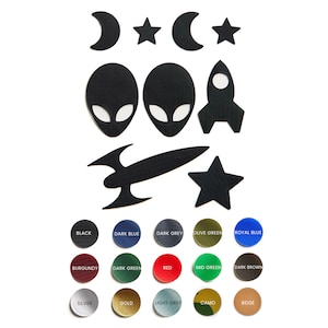 Könnte beinhalten: Ein Set aus schwarzen, roten und blauen Bügelbildern mit verschiedenen Designs zum Thema Weltraum, darunter Außerirdische, Raketen, Sterne und Halbmonde. Die Bügelbilder sind auf einem weißen Hintergrund mit Farbmustern darunter angeordnet.