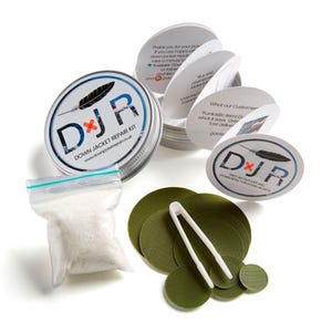 May include: A down jacket repair kit in a silver tin with a green and white logo that says "DJR Down Jacket Repair Kit". The kit includes a small bag of down feathers, a pair of tweezers, and a set of green fabric patches.