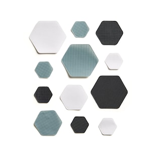 Può includere: Una collezione di toppe esagonali di colore bianco, nero e blu. Le toppe sono disposte a forma di nido d'ape.