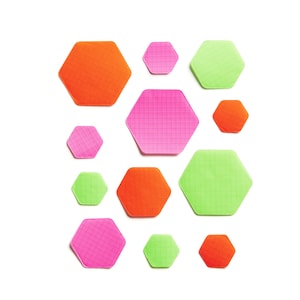May include: A collection of 10 colorful hexagonal sticky notes in pink, green, and orange. The notes are arranged in a honeycomb pattern.
