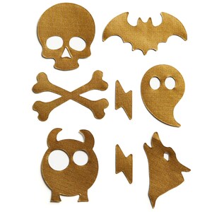 May include: A set of nine gold felt Halloween-themed cutouts. The cutouts include a skull, crossbones, bat, ghost, two lightning bolts, and two monsters.