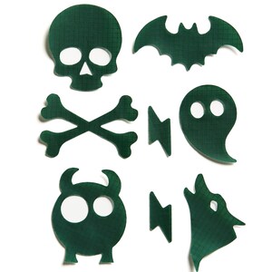 May include: A set of eight green Halloween-themed iron-on patches. The patches feature a skull and crossbones, a bat, a ghost, a monster, a wolf, and three lightning bolts.