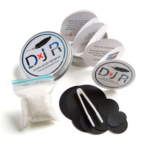 Może przedstawiać: Zestaw naprawczy do kurtek puchowych w srebrnym pudełku z białą etykietą z napisem "DJR Down Jacket Repair Kit" i ikoną pióra. Zestaw zawiera mały woreczek z puchem, pęsetę i kilka czarnych łat z tkaniny.