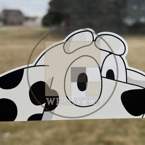 May include: A flat, die-cut sticker featuring a cartoon dog head with white fur, black spots, and large eyes. The design includes a black nose and ears, with the text WEMAYKE printed in white letters over a square watermark overlaying the center.