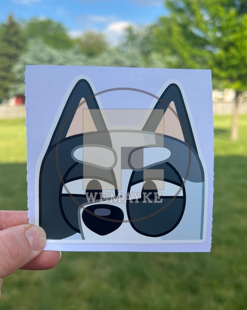 May include: A square sticker featuring a stylized cartoon dog face with blue and grey fur, large dark eyes, and pointed ears. The design includes a watermark with the text WEMAYKE overlaid in the center of the sticker on a white background.