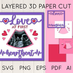 May include: A layered 3D paper cut design with the text "Love at First Heartbeat". The design features a sonogram image, hearts, and the word "Love" in a decorative font. The color scheme includes purple, pink, and white.