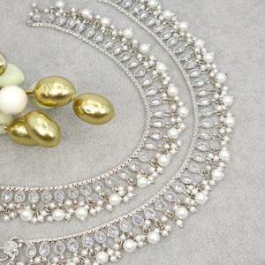 May include: Two silver anklets with white pearl and clear crystal accents.
