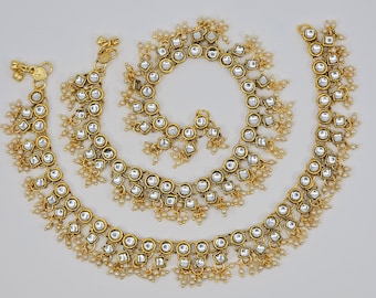 May include: A set of three gold anklets with dangling pearl beads and mirrored square accents.
