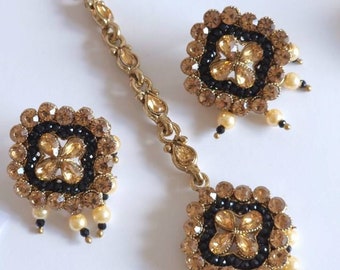 May include: A gold-tone hairpiece with a black and amber stone design. The hairpiece has a dangling chain with a similar design and pearl accents.