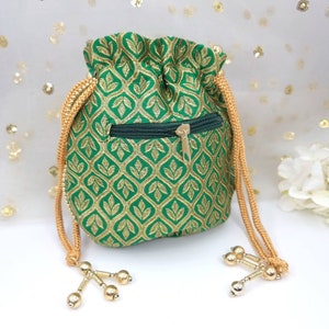 Puede incluir: Una bolsa de cord&oacute;n verde con un patr&oacute;n floral dorado y un bolsillo con cremallera. La bolsa tiene borlas doradas con cuentas.
