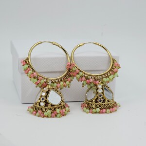 Peut inclure: Une paire de boucles d'oreilles créoles dorées avec des franges de perles roses et vertes et un pendentif en forme de larme en miroir.