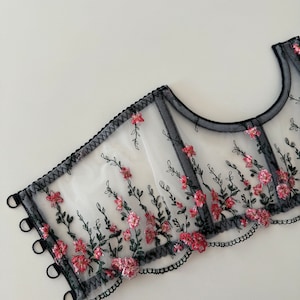 Peut inclure: Top de lingerie en mesh noir avec broderie florale rose et verte. Le haut a un bord festonn&eacute; et des bretelles r&eacute;glables.