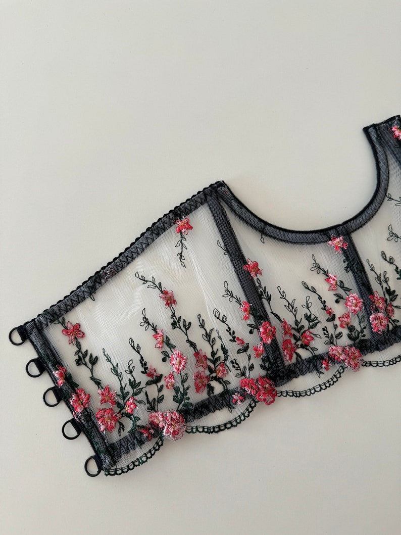 Peut inclure: Top de lingerie en mesh noir avec broderie florale rose et verte. Le haut a un bord festonn&eacute; et des bretelles r&eacute;glables.