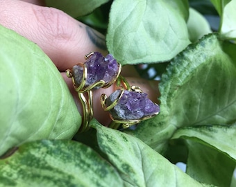 May include: Two gold rings with amethyst crystals. The rings are made of wire and the amethyst crystals are a deep purple color.