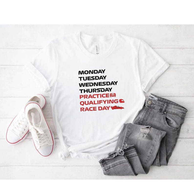 Puede incluir: Camiseta blanca con texto negro y rojo que enumera los d&iacute;as de la semana y los t&eacute;rminos de carreras. El texto incluye "Lunes" a "D&iacute;a de carrera" con un gr&aacute;fico de coche de carreras. La camiseta se combina con vaqueros grises y zapatillas blancas.