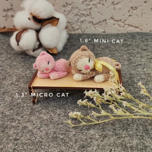 May include: Two crocheted cat toys, one pink and one brown, lying on a wooden platform. The pink cat is labeled "1.3" MICRO CAT" and the brown cat is labeled "1.6" MINI CAT".