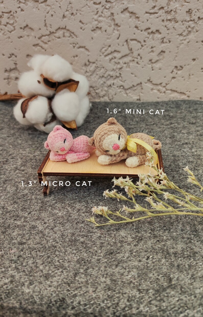 May include: Two crocheted cat toys, one pink and one brown, lying on a wooden platform. The pink cat is labeled "1.3" MICRO CAT" and the brown cat is labeled "1.6" MINI CAT".