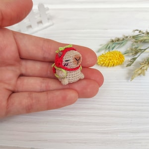 Könnte beinhalten: Ein kleines gehäkeltes Tier, das einen roten und grünen Hut trägt. Das Tier sitzt in der Handfläche.