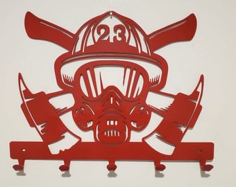 May include: Red metal firefighter key holder with a firefighter helmet, gas mask, and crossed axes. The helmet has the number 23 on it.