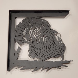 May include: Black metal shelf bracket with a cutout design of a turkey. The turkey is facing to the right and has detailed feathers.