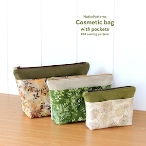 May include: Three cosmetic bags with pockets in varying sizes. The bags feature a green top with a brown zipper and a patterned bottom. The patterns include floral and leaf designs in shades of green, yellow, and beige. The text on the image says "Cosmetic bag with pockets PDF sewing pattern."