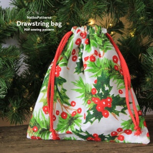 May include: A white drawstring bag with a red holly berry and green leaf print. The bag has red drawstrings.  The bag is sitting on a wooden surface.  NatkoPatterns Drawstring bag PDF sewing pattern.