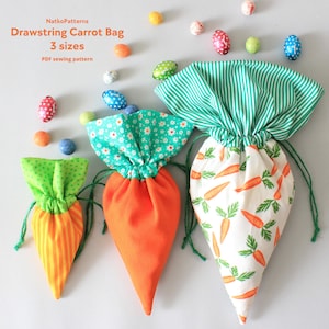 May include: Three drawstring carrot bags in different sizes. The smallest bag is green and orange striped, the middle bag is orange, and the largest bag is white with a carrot print. All bags have green drawstrings.
