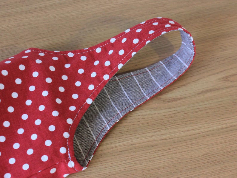May include: Red and white polka dot fabric with a gray and white striped fabric sewn to the back. The fabric is folded over to create a strap.