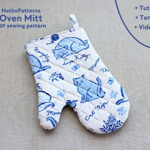 May include: White oven mitt with blue cat illustrations and text. The mitt features a quilted pattern and a hanging loop. Text on the mitt includes "NatkoPatterns Oven Mitt PDF sewing pattern", "Naughty", "Lop Kitty", "Meow", and "Cat Nip".