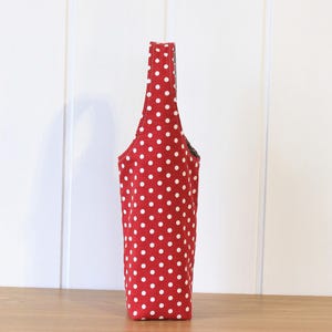 May include: A red and white polka dot tote bag with a black handle.