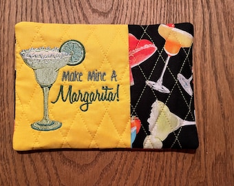 Può includere: Presa calda trapuntata gialla con una margarita ricamata e il testo "Make Mine A Margarita!" Un lato della presa calda è nero con un motivo di cocktail colorati.