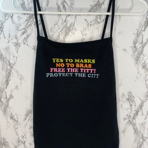 May include: Black spaghetti strap tank top with the text "YES TO MASKS NO TO BRAS FREE THE TITTTY PROTECT THE CITY" in rainbow colors.