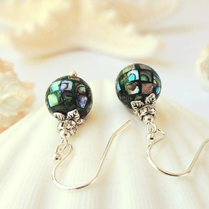 May include: A pair of silver dangle earrings with green and iridescent abalone shell bead drops.