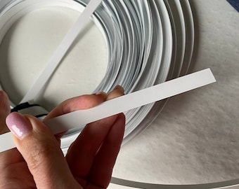 Op de afbeelding: Een rol witte, flexibele metaaldraad, met een enkel stuk draad dat rechtgetrokken is en in een hand wordt gehouden. De draad wordt gebruikt voor het maken van gezichtsmaskers.