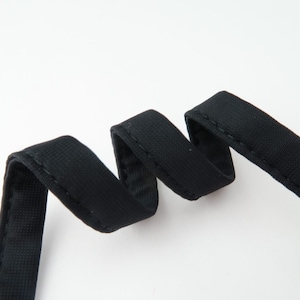 May include: Black elastic trim with a stitched edge. The trim is about 1/2 inch wide.
