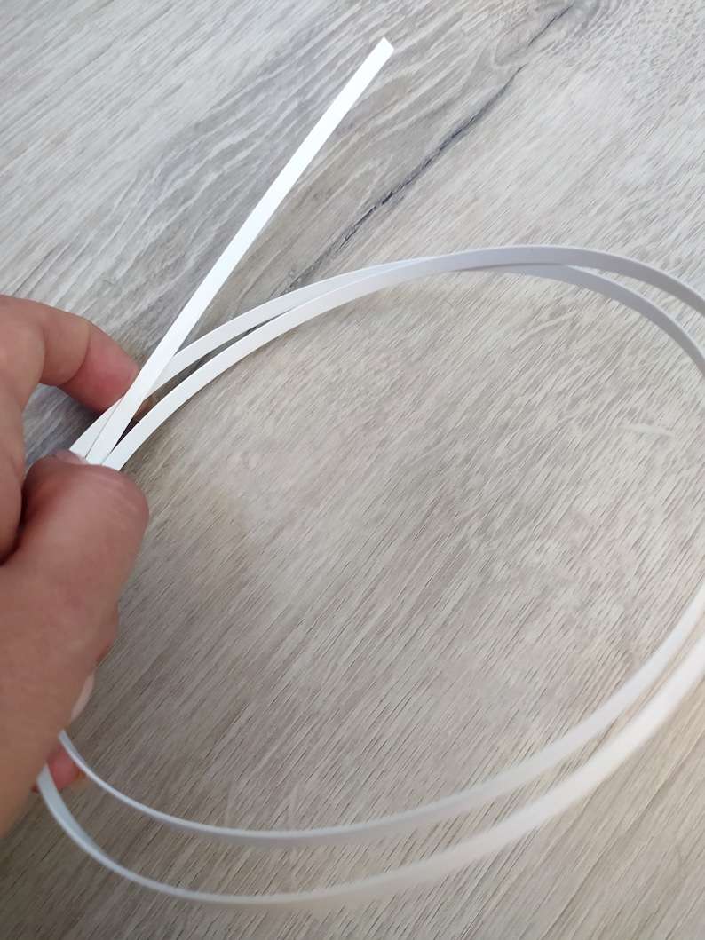 Op de afbeelding: Twee witte plastic strips, &eacute;&eacute;n recht en &eacute;&eacute;n gebogen in een cirkel.
