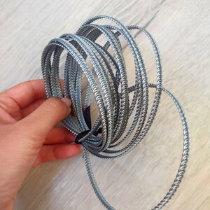 Op de afbeelding: Een stapel zilveren gevlochten draadringen. De ringen zijn allemaal even groot en zijn op elkaar gestapeld.
