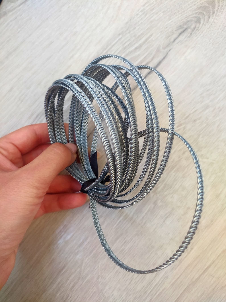 Op de afbeelding: Een stapel zilveren gevlochten draadringen. De ringen zijn allemaal even groot en zijn op elkaar gestapeld.