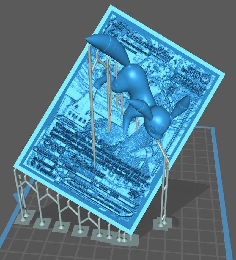 May include: 3D-printed model of a blue Umbreon Pokémon card with a miniature Umbreon figure. The card displays Umbreon's stats and abilities, including 'Dark Signal' and 'Max Darkness'. The model is supported by a structure of thin, light gray rods and bases, suggesting a 3D printing support system. The overall color scheme is cool-toned, with light blue dominating the card and figure, and gray in the support structure.