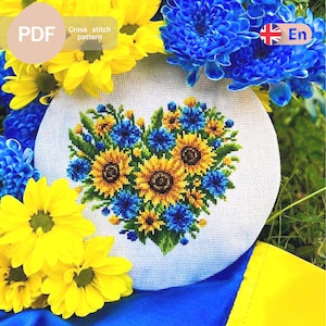 Könnte beinhalten: Ein PDF-Kreuzstichmuster mit einem herzförmigen Arrangement aus gelben Sonnenblumen und blauen Kornblumen auf weißem Aida-Stoff. Das Design ist von frischen gelben und blauen Blumen umgeben, mit Textbeschriftungen für PDF und En.