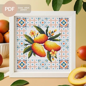 Könnte beinhalten: Ein gerahmtes Kreuzstichmuster mit drei Mangos mit grünen Blättern und kleinen gelben Blüten. Das Design ist vor einem weißen Hintergrund mit einem geometrischen Muster in Orange, Blau und Weiß angeordnet. Der Rahmen ist weiß, und der Text "PDF Cross stitch pattern" befindet sich oben links.