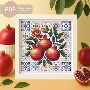 May include: A framed cross-stitch pattern featuring three red pomegranates with green leaves and floral accents. The pattern is set against a white background with a decorative border. The text "PDF Cross stitch pattern" is in the upper left corner.