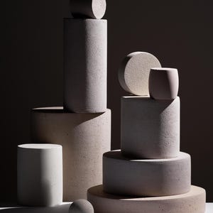 Set of handmade concrete display pedestals in various sizes arranged on dark background for product photography