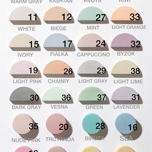 Puede incluir: Una carta de colores con 24 muestras de pintura semicirculares en varios tonos pastel. Cada muestra est&aacute; etiquetada con un nombre de color y un n&uacute;mero, incluyendo tonos como "Warm Gray", "Mint", "Light Pink" y "Yellow".