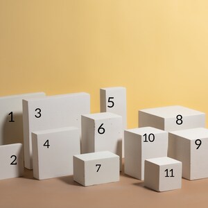 Pode incluir: Uma variedade de onze blocos brancos retangulares e c&uacute;bicos de v&aacute;rios tamanhos. Os blocos est&atilde;o dispostos sobre uma superf&iacute;cie marrom contra um fundo amarelo. Os blocos s&atilde;o numerados de 1 a 11.