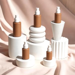 Concrete display riser set for cosmetics, minimal product display stands with skincare bottles, retail merchandising display system for beauty brands