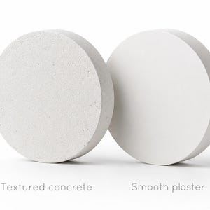 Pode incluir: Dois objetos circulares, um com superf&iacute;cie de concreto texturizado, o outro com acabamento de gesso liso. O texto abaixo diz "Textured concrete" e "Smooth plaster". Os objetos s&atilde;o de cor branco sujo.