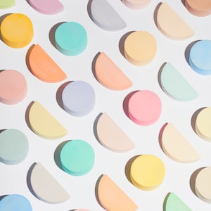 May include: A flat lay of pastel colored circles and half circles arranged in a diagonal pattern on a white background.